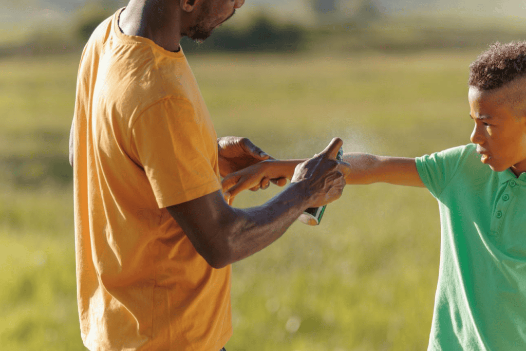 A father applying bug repellant to his son's arm.